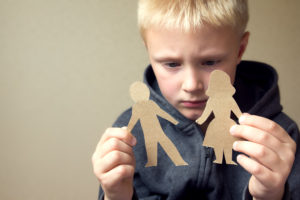 Kind hält zerrissene Papierfiguren in der Hand
