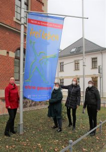 Vier Frauen hissen eine blaue Fahne