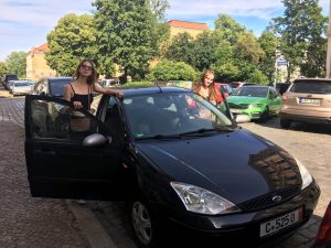 zwei Frauen an der geöffneten Autotür, schwarzes Auto